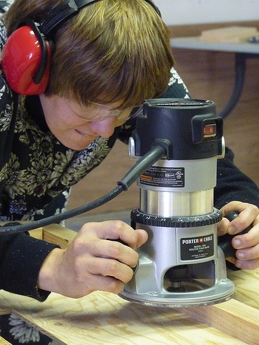 Julia holding a router bent over a board
