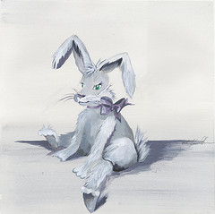 White rabbit with floppy ears and red bow sitting on floor