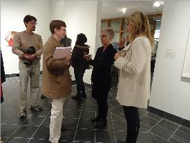 Three people speak in an ar gallery with visitors in the background. Garland-Thompson dressed in black is in the middle.